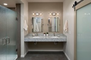 A contemporary universal design bathroom features a dual, roll-under vanity and a curbless shower with frosted glass doors.